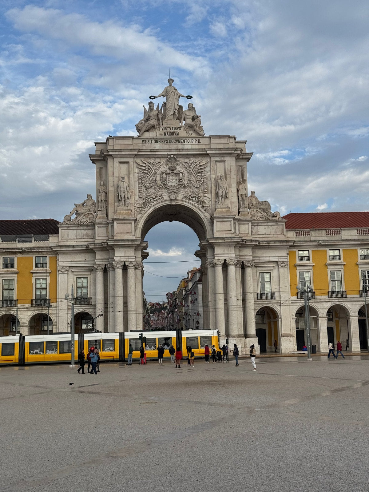 The Arco da Rua Augusta on Praça do Comércio, with a yellow tram passing below the arcades